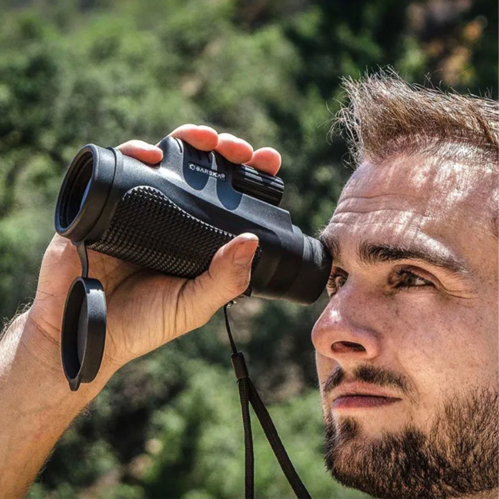 Man die door een zwarte compacte Barska monokulair verrekijker kijkt in een natuurlijke omgeving