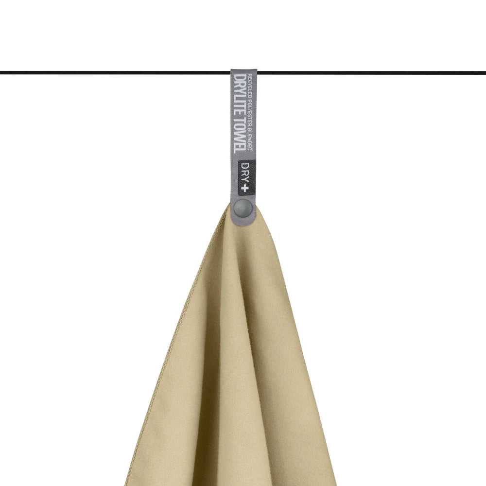De Sea to Summit Drylite Towel reishanddoek in het beige hangt aan een dunne lijn met de grijze Dry+ drukknoplus.