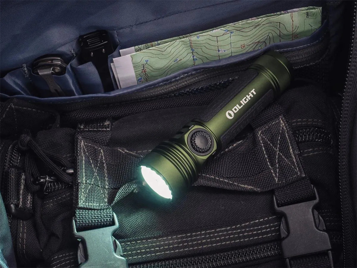 Olight Seeker 4 Pro OD Green olijfgroene oplaadbare LED zaklamp met ingeschakeld licht op een zwarte tas met kaart