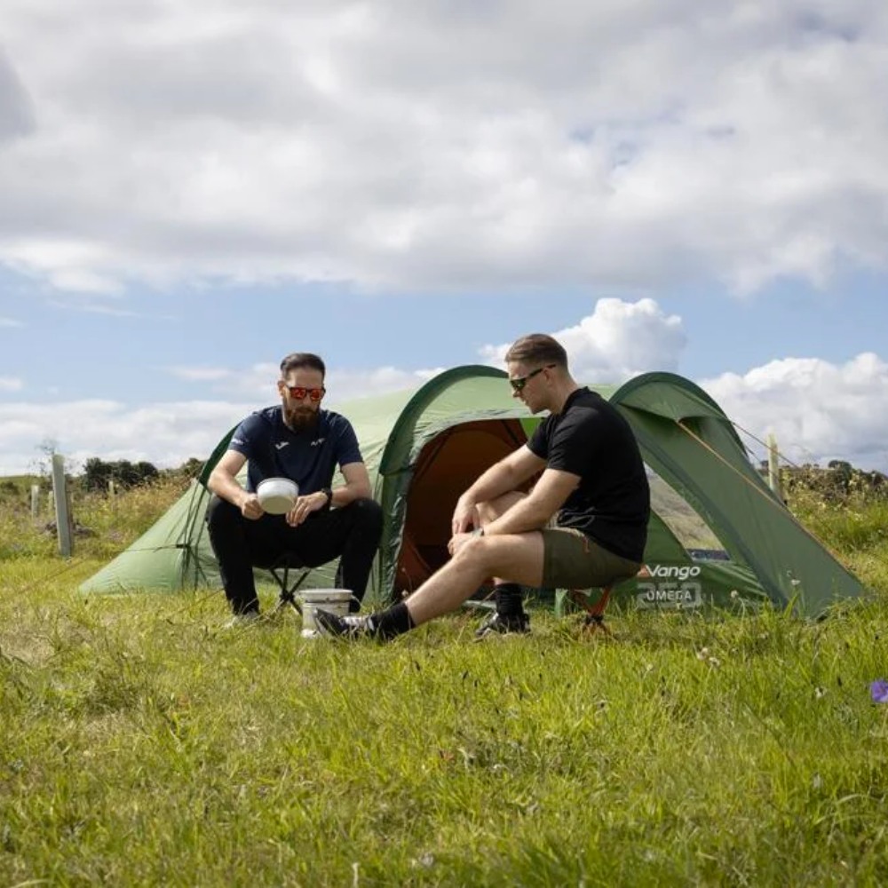 Vango Omega 350 groene 3-persoons tunnelcent opgezet in een grasland met twee personen ervoo