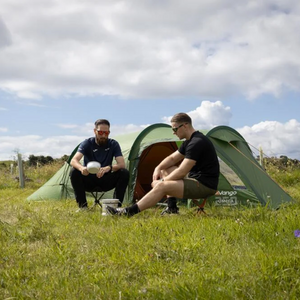 Vango Omega 350 groene 3-persoons tunnelcent opgezet in een grasland met twee personen ervoo